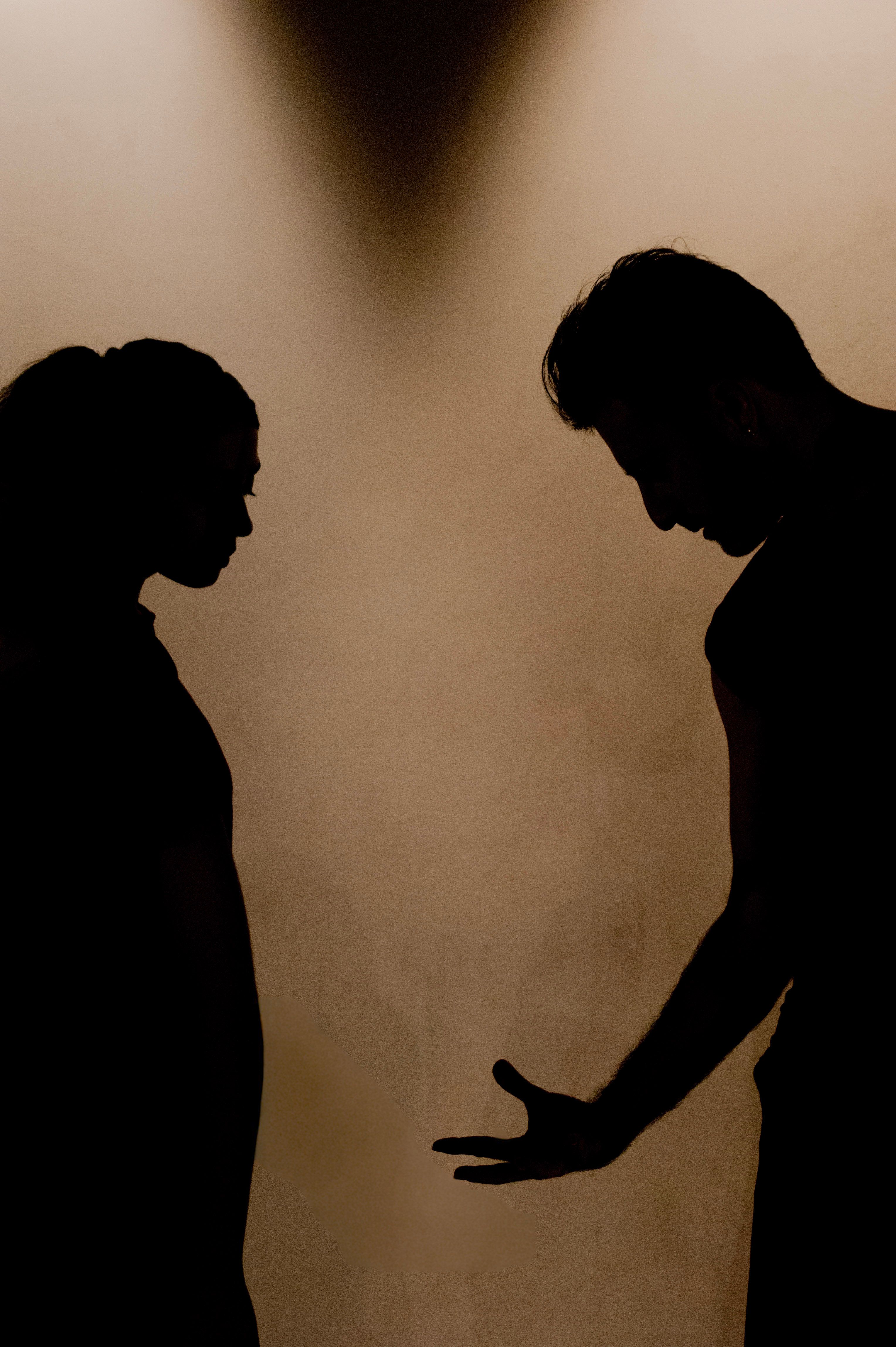 Silhouettes of two people in a tense private conversation